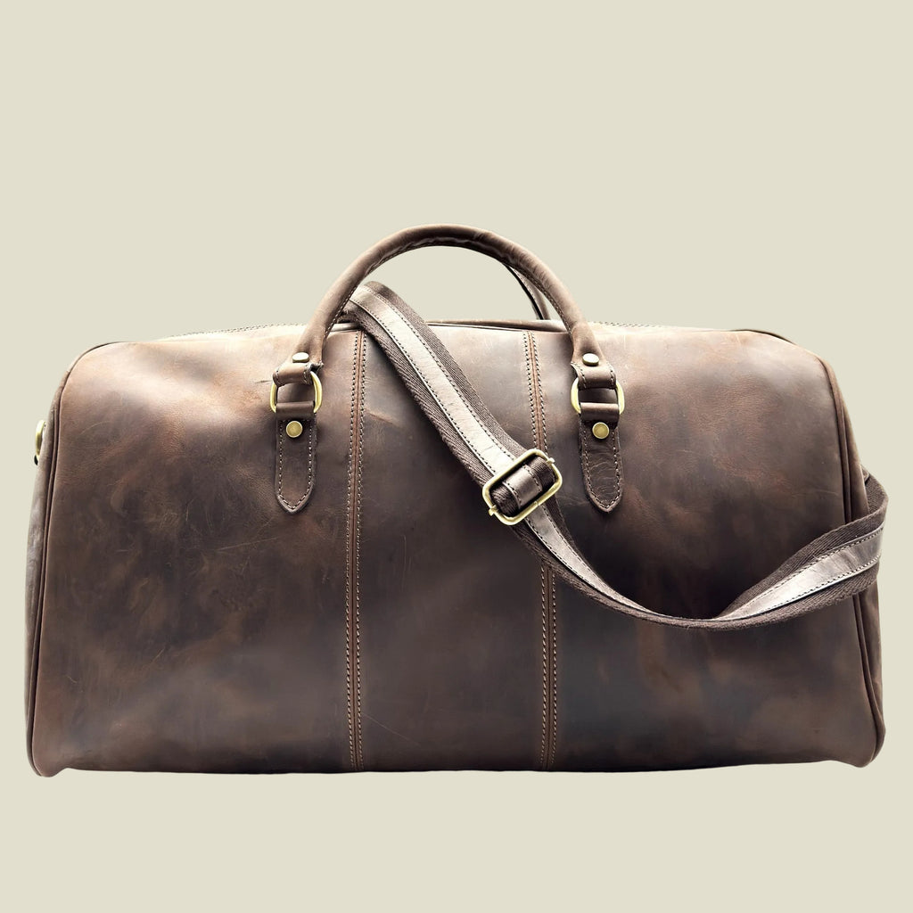 A dark brown distressed leather duffel bag with double top handles, a detachable shoulder strap, and brass-tone hardware, shown against a plain white background.