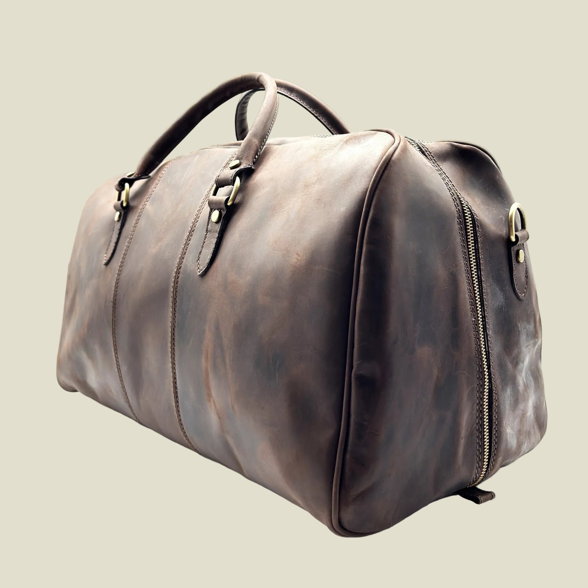 A dark brown distressed leather duffel bag with gold-tone hardware, shown from a three-quarters angle on a white background.