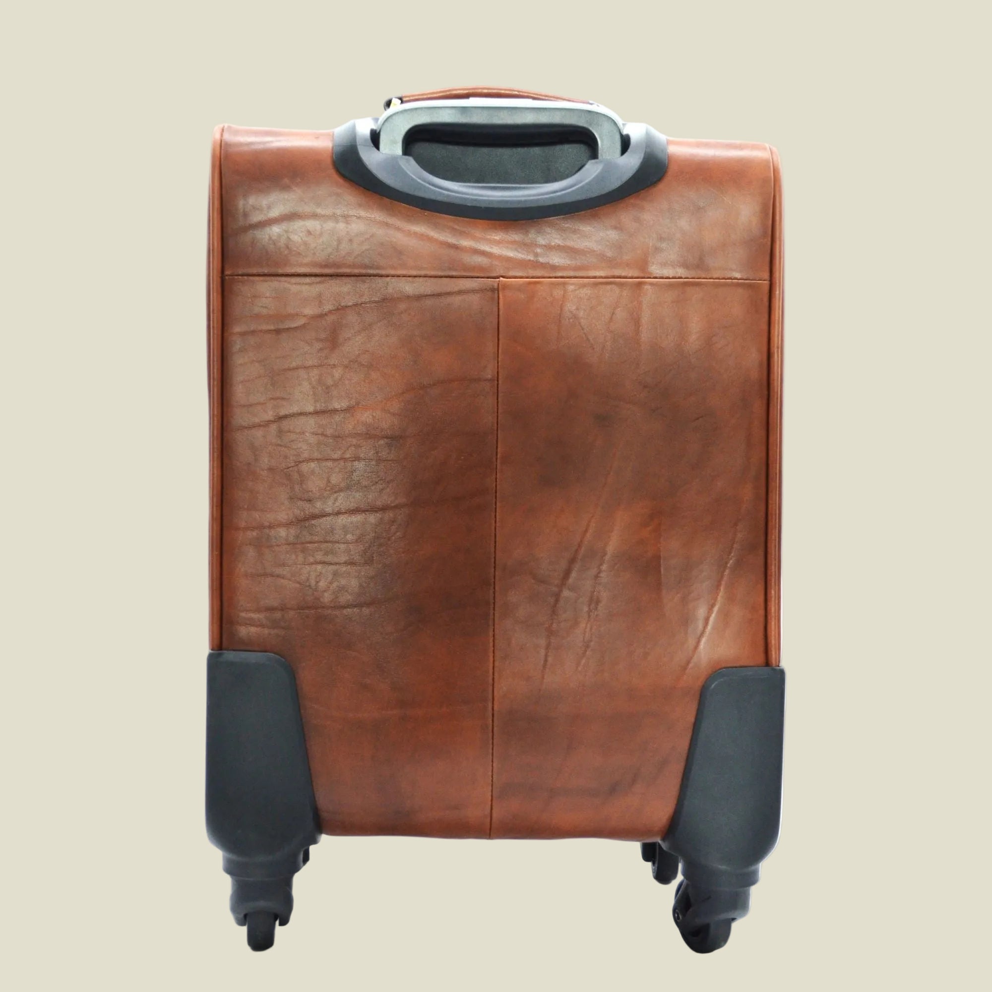 A brown leather rolling suitcase with black wheels and protective corner guards, shown from the back on a white background.