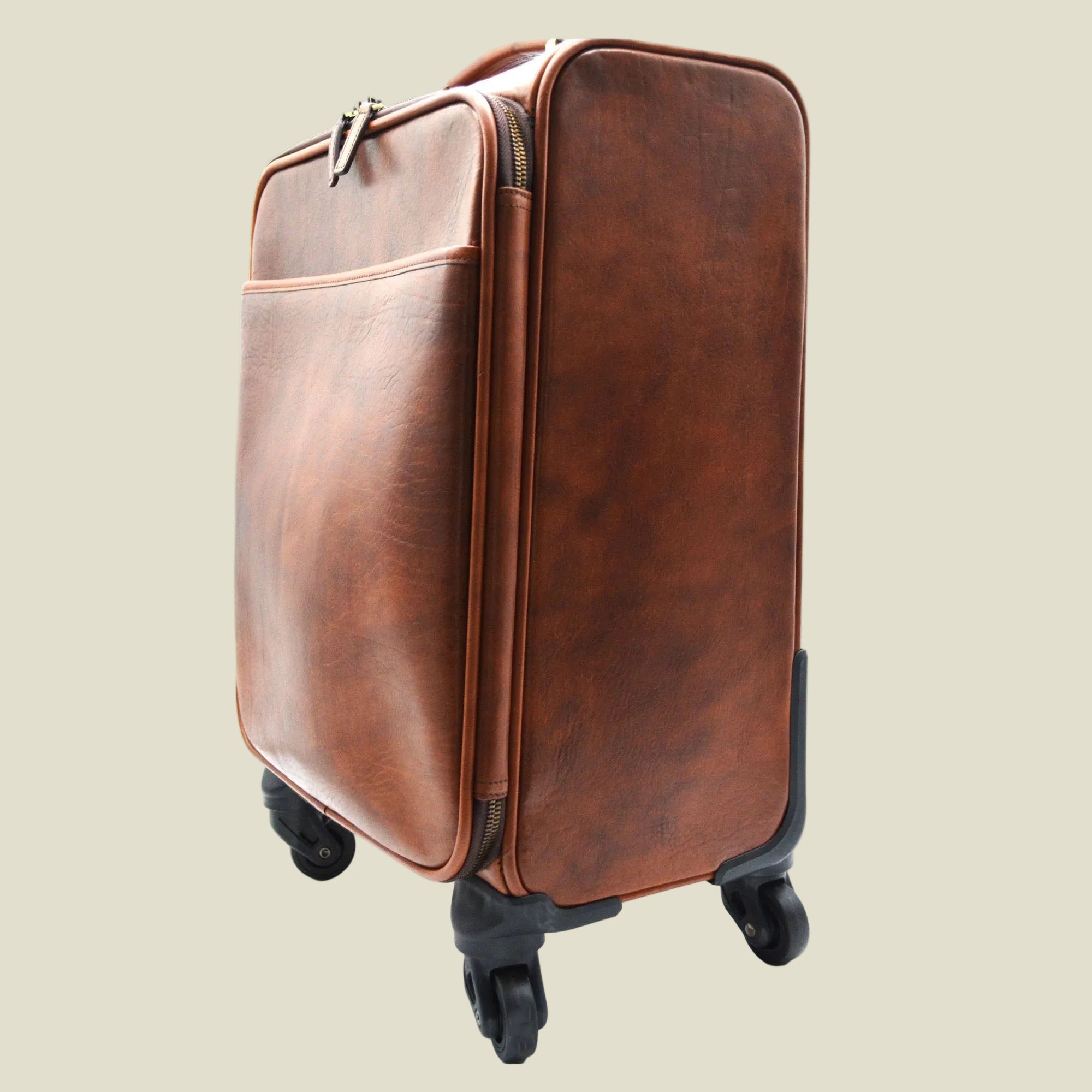 A brown leather rolling suitcase with black spinner wheels, shown from a three-quarter angle against a white background.
