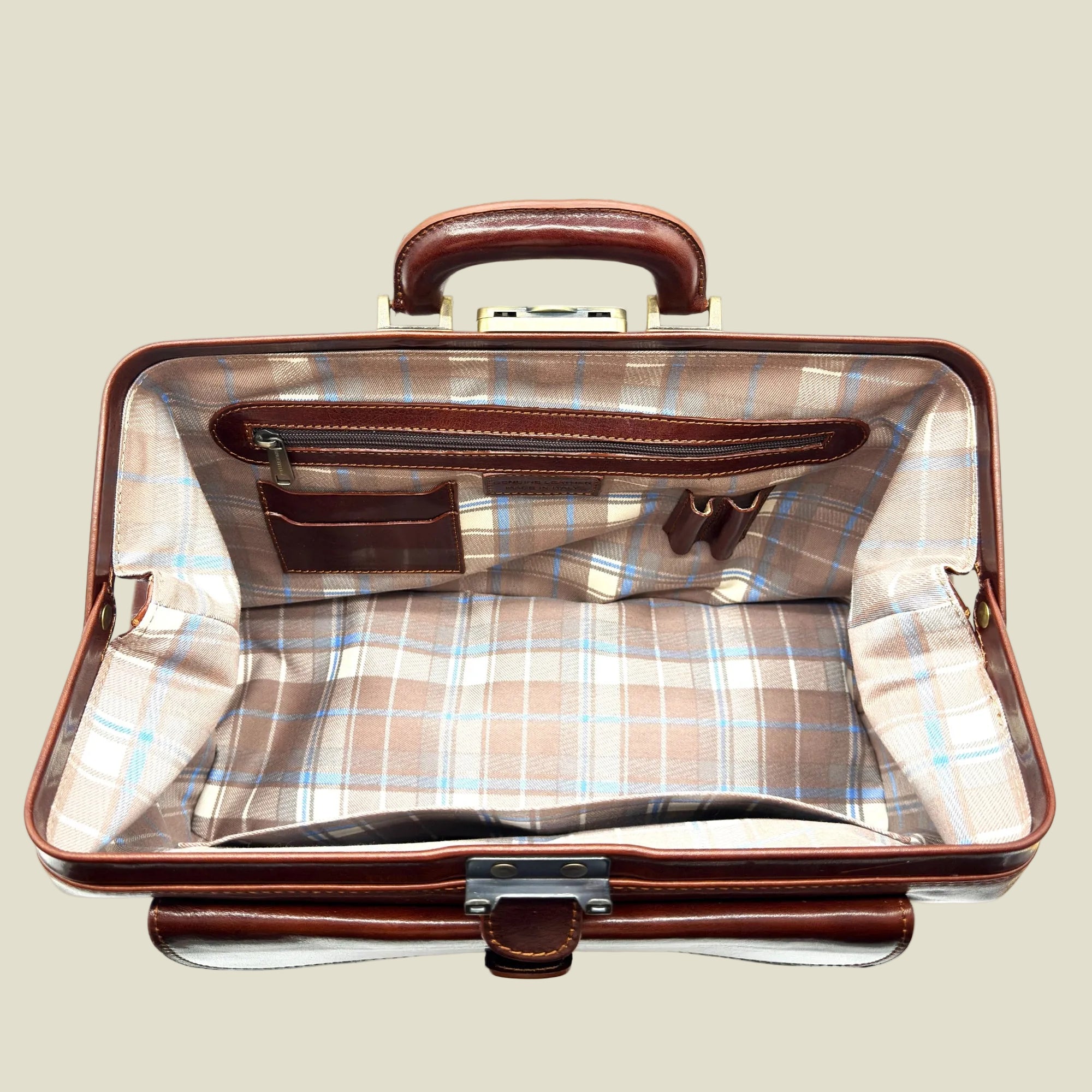 An open vintage-style briefcase or travel bag with a brown leather handle and trim, featuring a beige and light blue plaid lining.