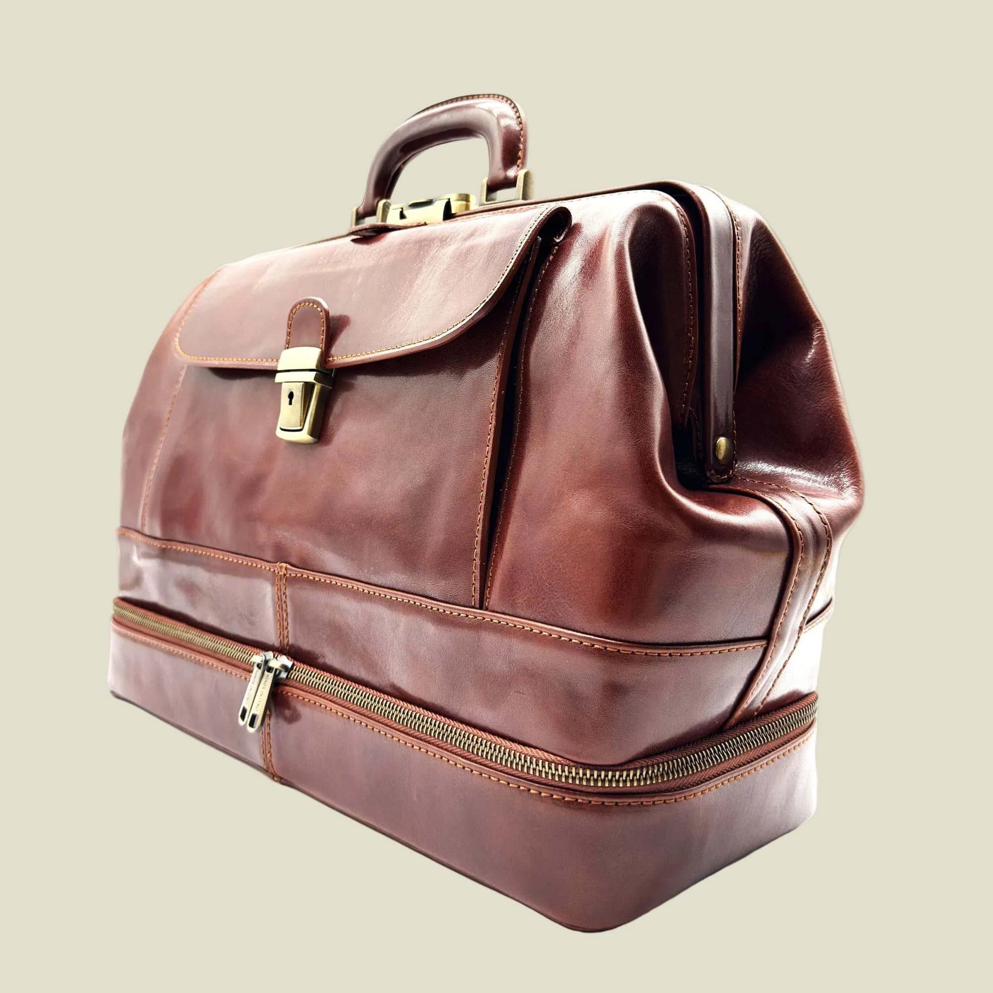 A brown leather briefcase with a top handle, a front flap secured by a brass clasp, and a lower zippered compartment, shown on a white background.