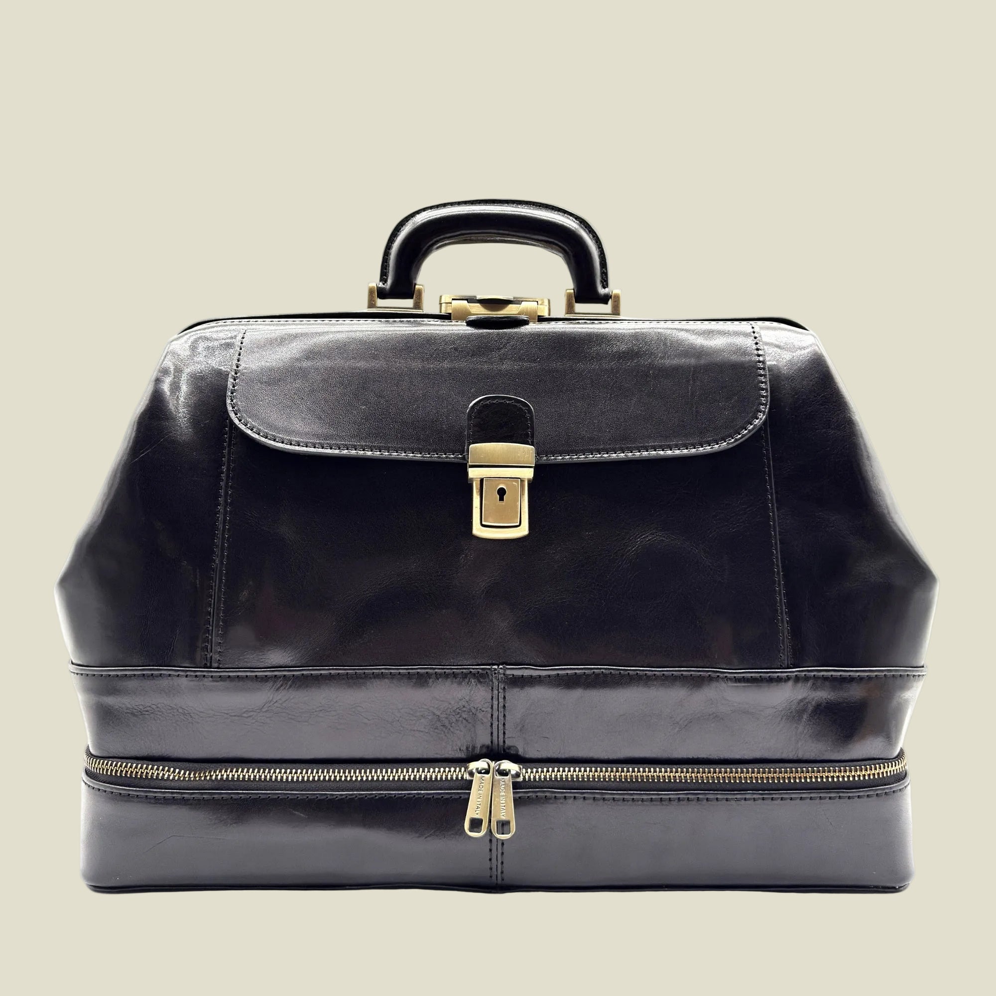 A black patent leather doctor case with gold-tone hardware, featuring a top handle, front flap with a lock, and a lower zipper compartment, shown against a plain white background.