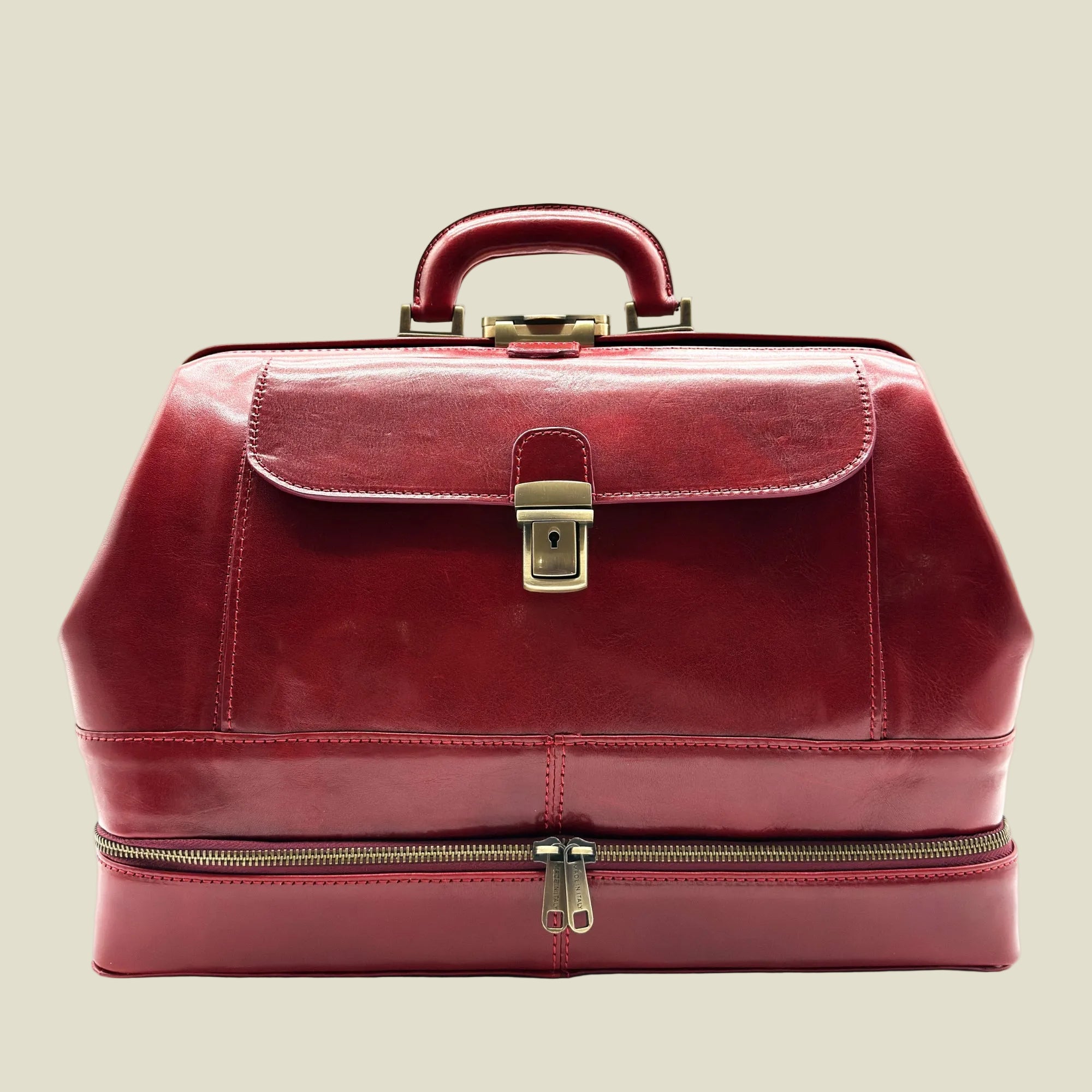 A burgundy red leather doctor case with a top handle, front flap, brass lock, and a zippered lower compartment, shown against a plain white background.