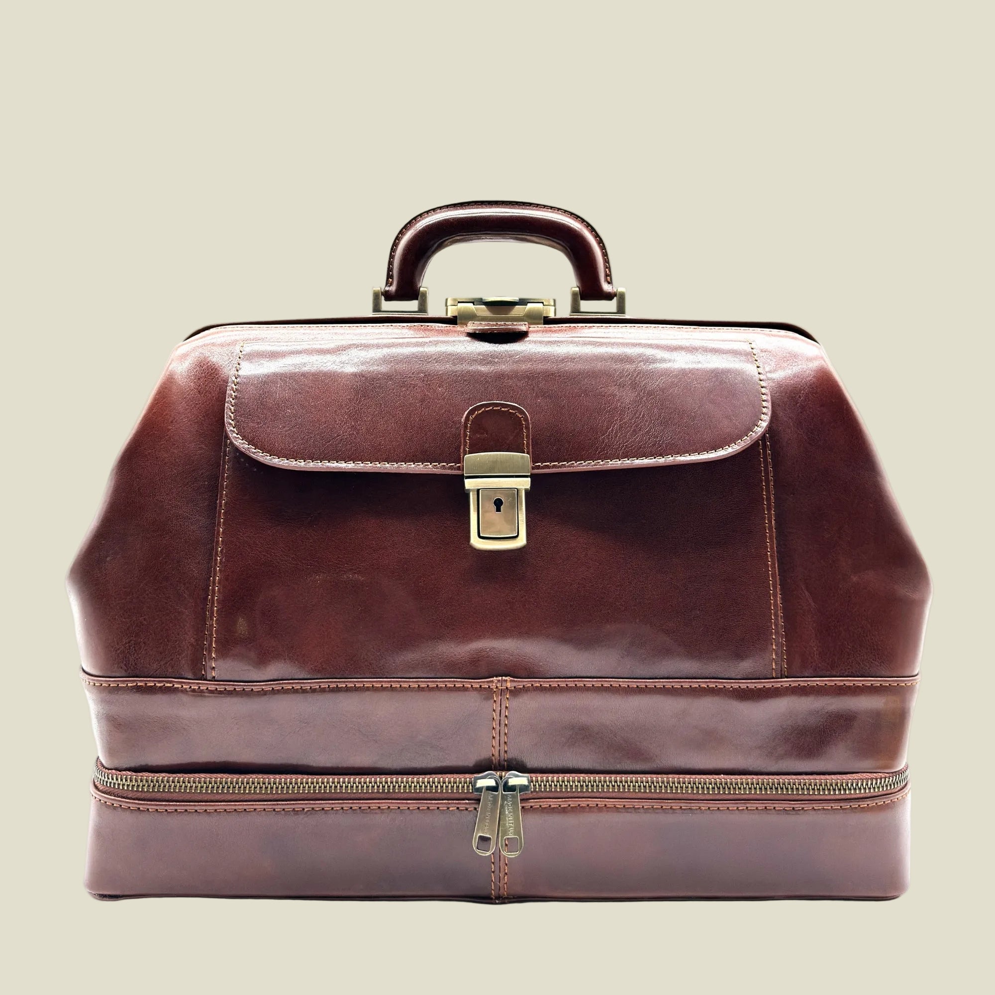 A dark brown leather doctor's bag with a top handle, a front flap secured by a brass lock, and a zippered lower compartment, shown against a plain white background.