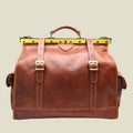 Brown leather bag with gold buckles on a white background