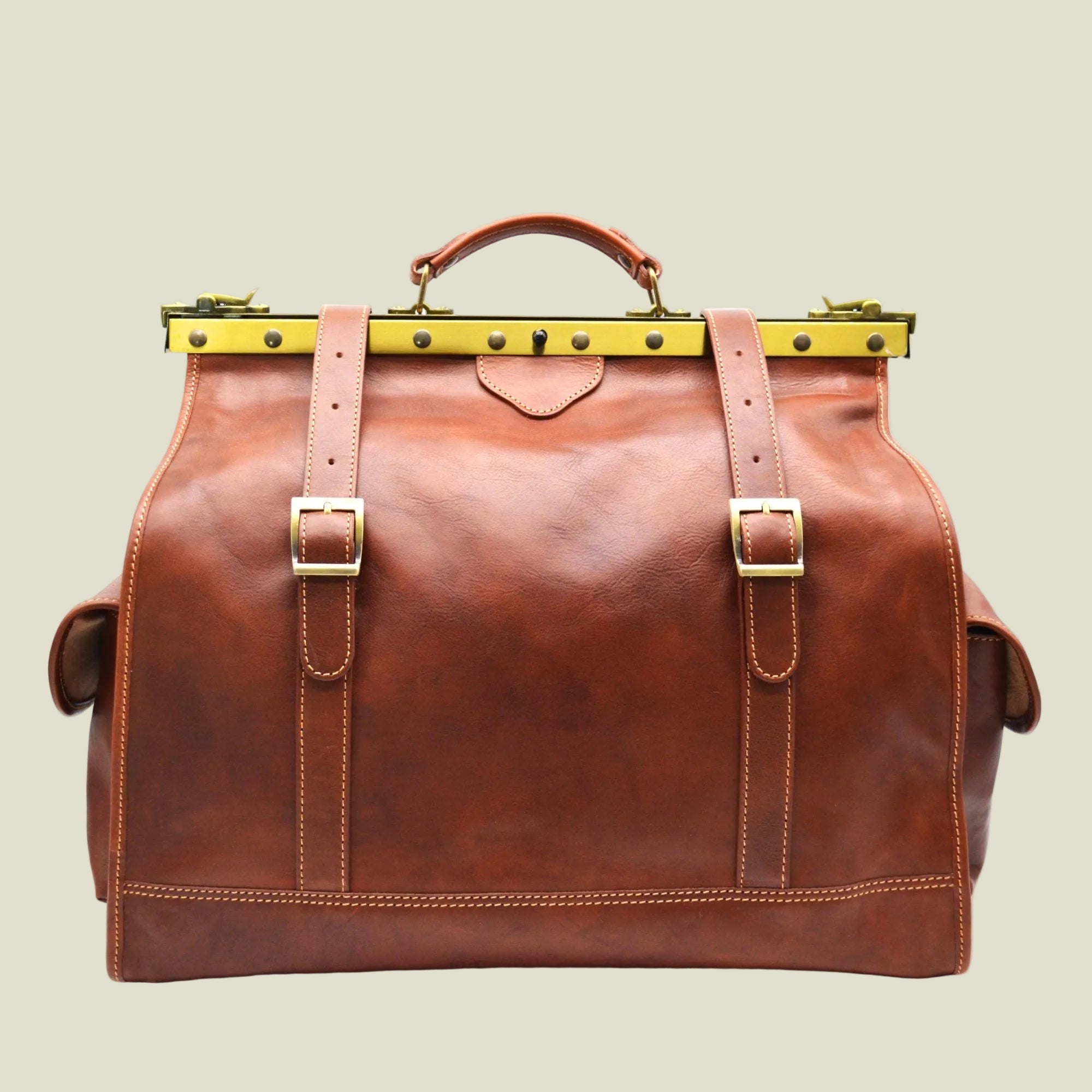 Brown leather bag with gold buckles on a white background