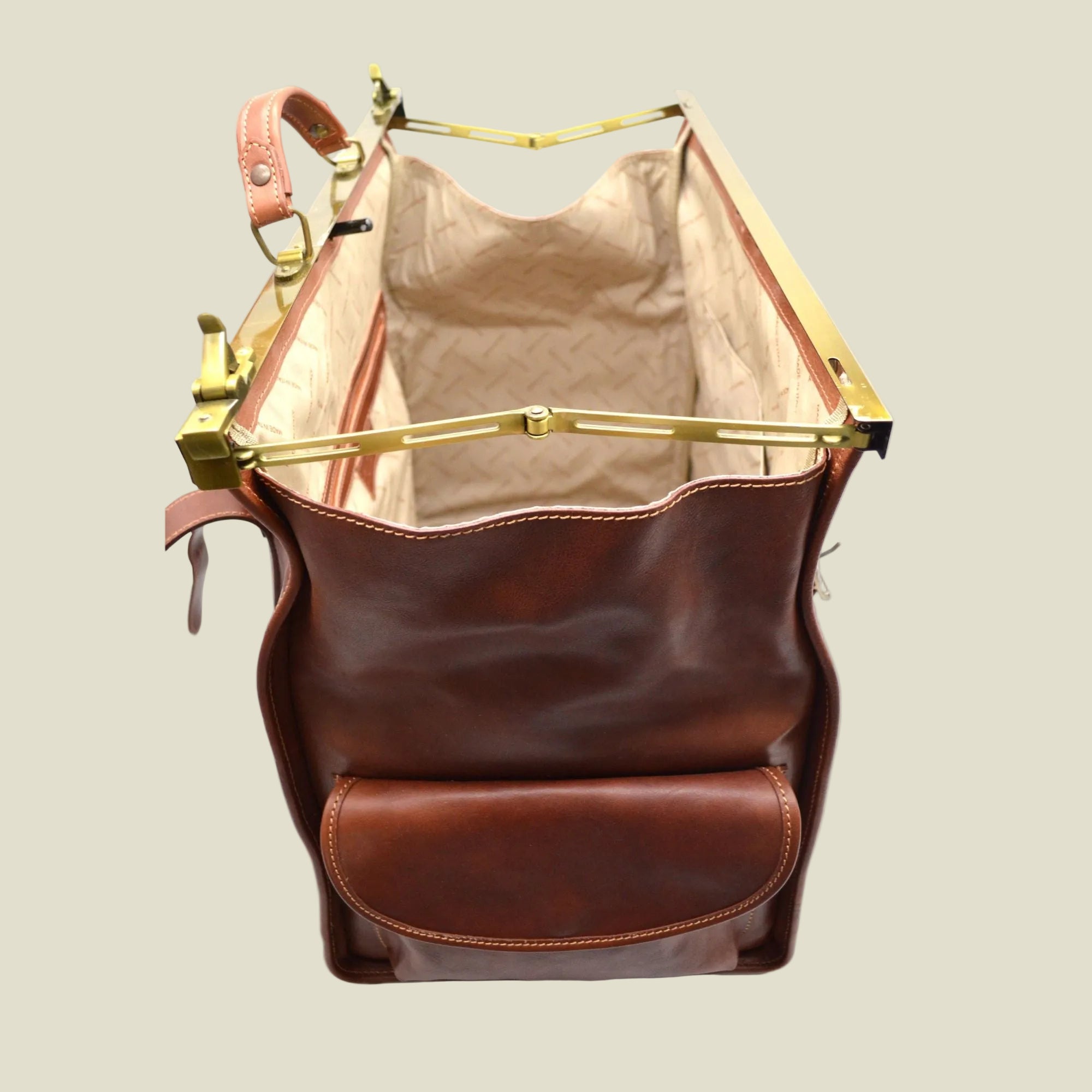 A brown leather handbag shown open from above, featuring a warm brown leather exterior, a tan quilted interior lining, and gold-tone metal hardware.