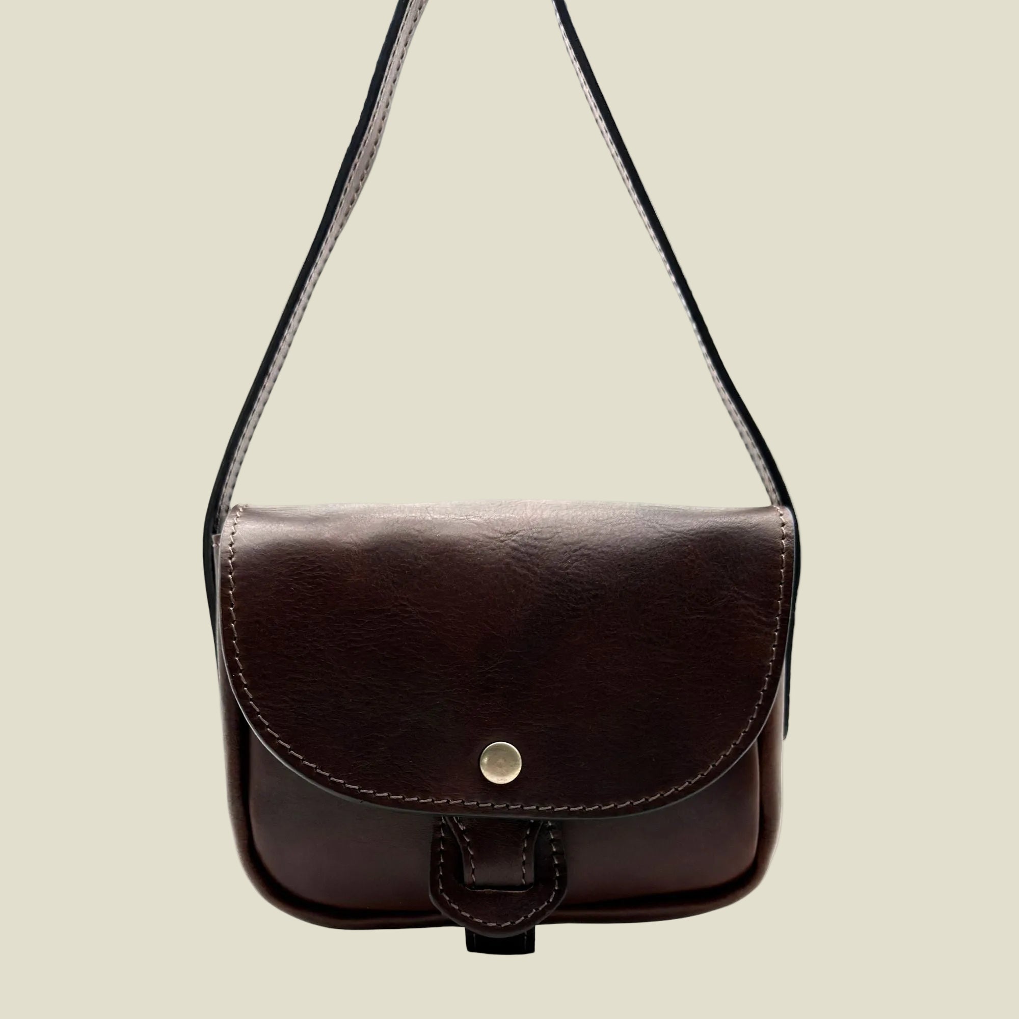 A dark brown leather crossbody bag with a single adjustable strap, a flap closure, and a small gold snap button, shown against a plain white background.