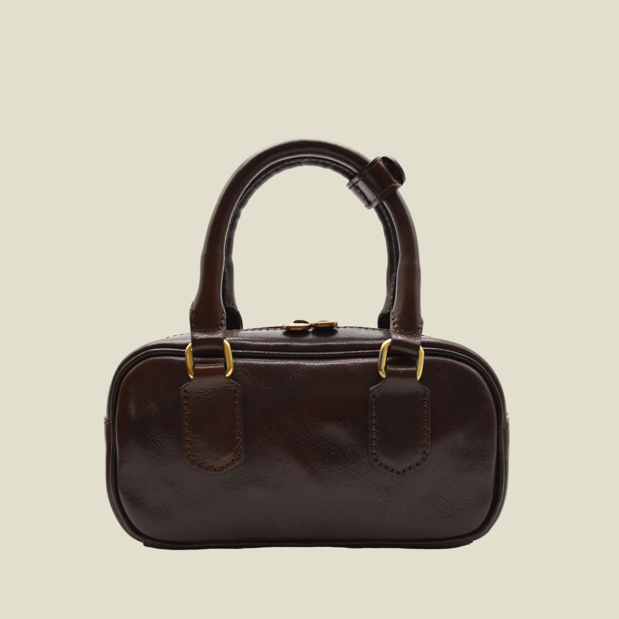 A dark brown leather handbag with a rounded rectangular body, double top handles, and gold-tone hardware, shown against a plain white background.