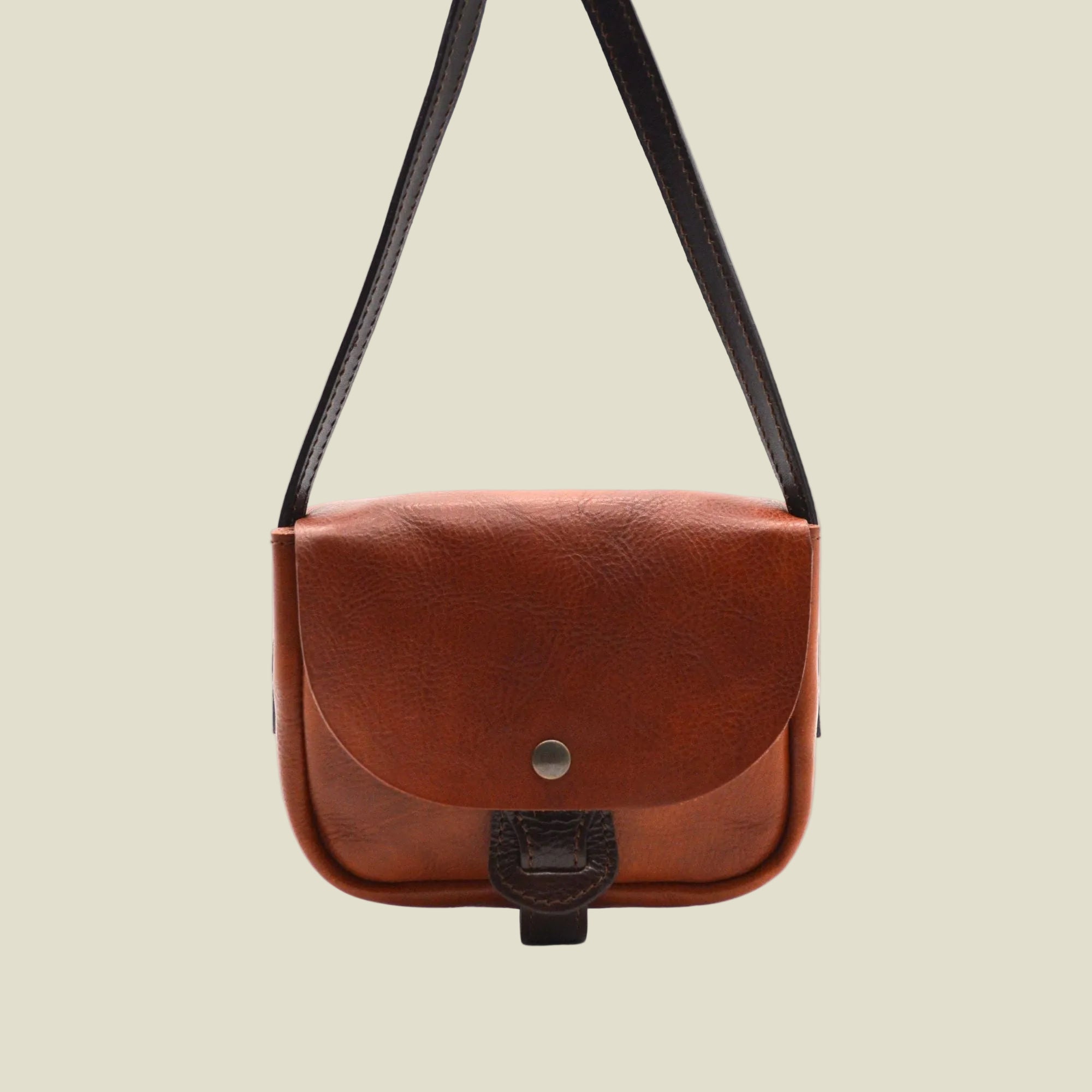 A brown leather crossbody bag with a dark brown strap and a snap-button closure on a plain white background.