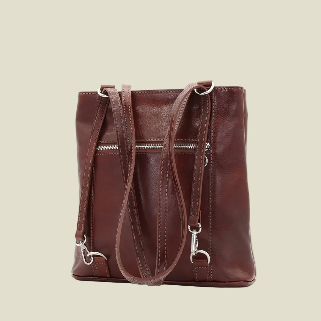 A dark brown leather tote bag with dual shoulder straps, a front zippered pocket, and silver-tone hardware, shown against a plain white background.