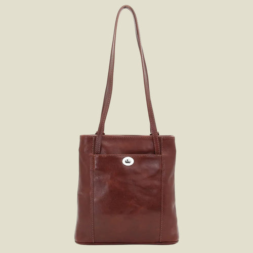 A brown leather tote bag with a single shoulder strap and a front pocket featuring a small silver-tone metal emblem, shown against a plain white background.