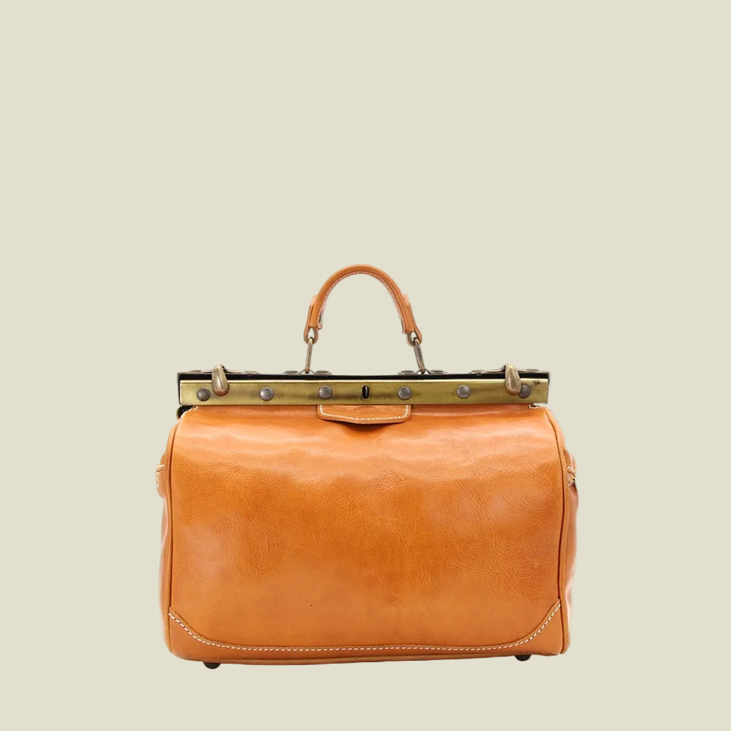 A vintage-style tan leather handbag with a top handle, a gold-tone metal frame clasp at the top, and silver-tone hardware, shown against a plain white background.
