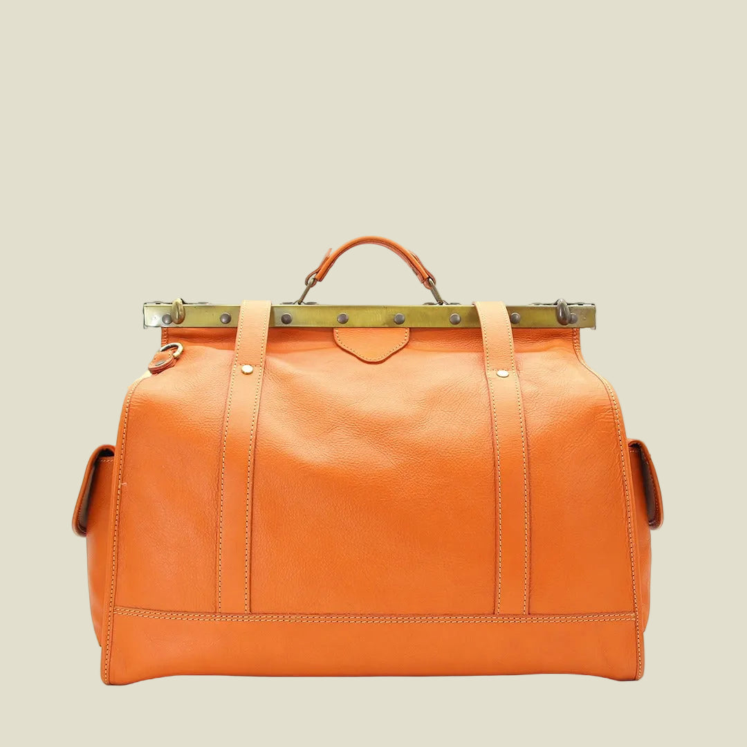 An orange leather duffel bag with a top handle, vertical stitched panels, and a brass-toned metal frame across the top, shown against a plain white background.