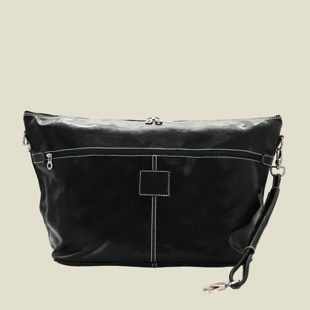 A black leather shoulder bag with white contrast stitching, featuring a top zipper, a front zip pocket, and a detachable wristlet strap with silver-tone hardware, shown against a plain white background.