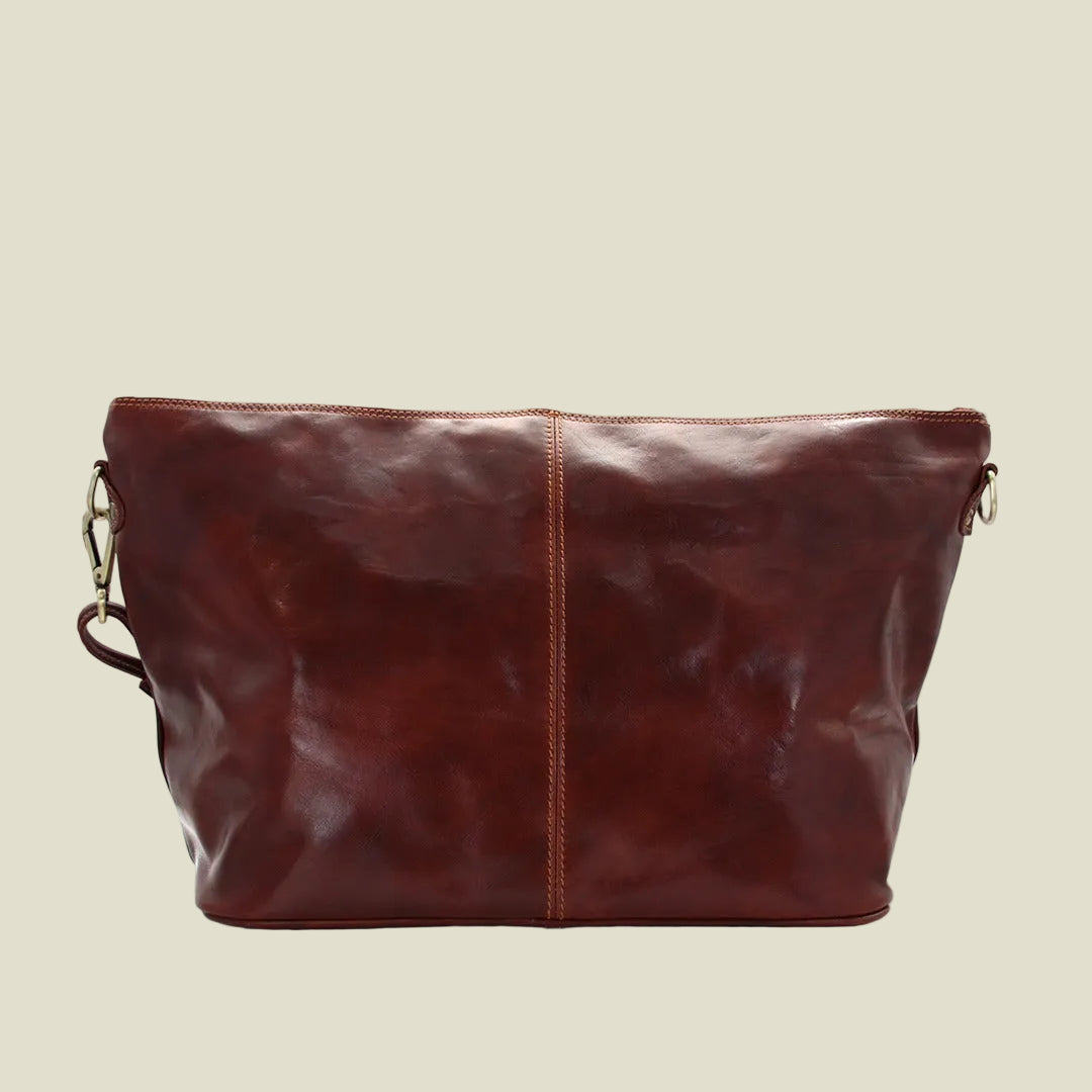 A dark reddish-brown leather shoulder bag with a vertical center seam, distressed texture, and gold-tone hardware, shown against a plain white background.