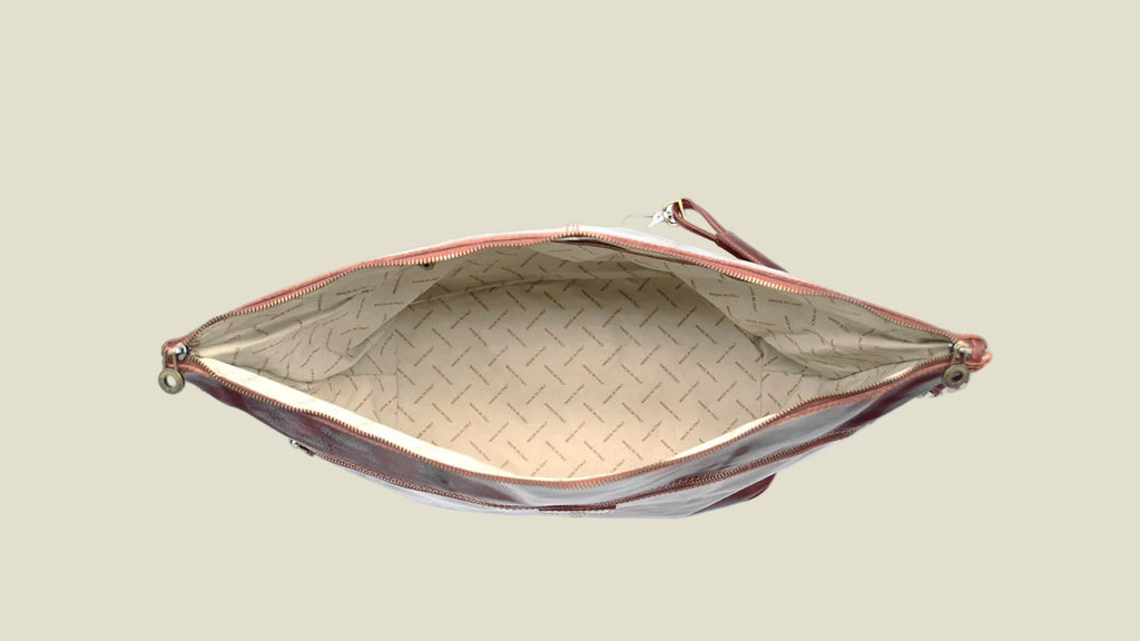 An open zippered clutch or pouch shown from above, featuring a beige patterned interior lining and a dark brown exterior with a matching wrist strap, set against a plain white background.