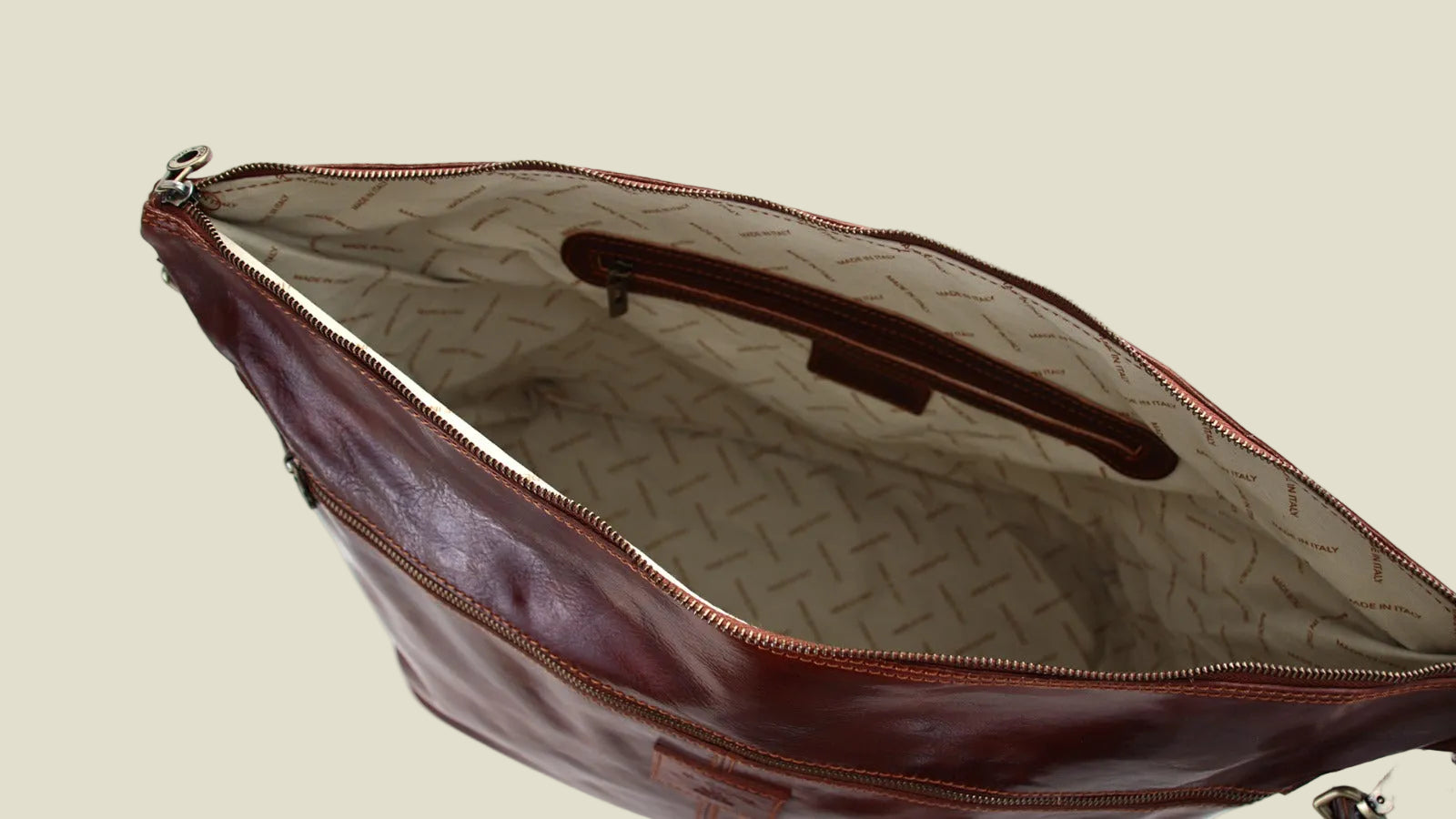 An open brown leather shoulder bag with a patterned beige interior lining, shown against a plain white background.