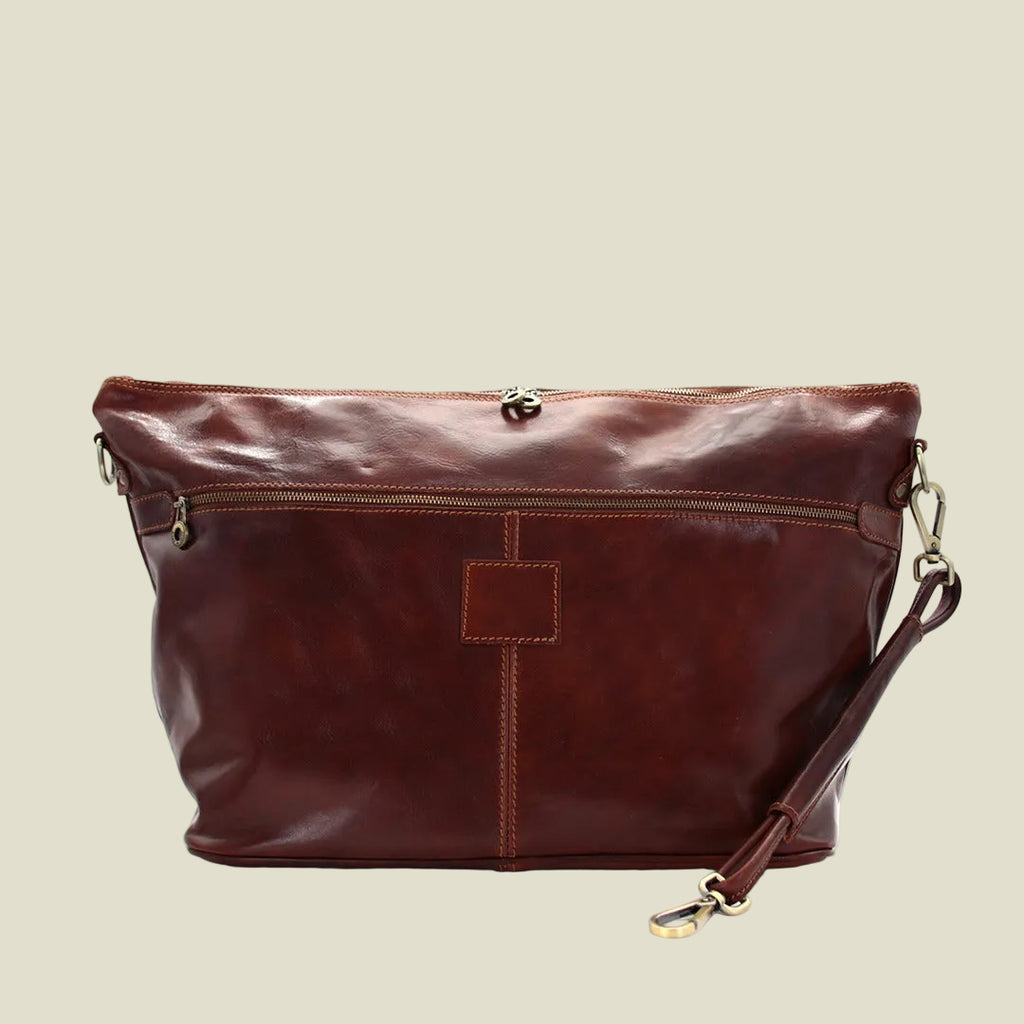 A dark reddish-brown leather shoulder bag with a front zippered pocket, a central vertical seam, and gold-tone hardware, shown on a plain white background.