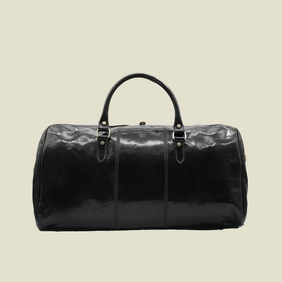 A black glossy patent leather duffel bag with dual top handles and gold-tone hardware, photographed against a plain white background.
