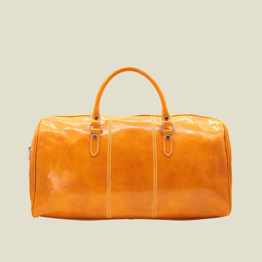 A glossy orange leather duffel bag with dual top handles, silver-tone hardware, and vertical contrast stitching, shown against a plain white background.